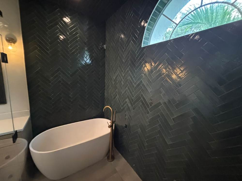 Herringbone tile bathroom wall with freestanding tub