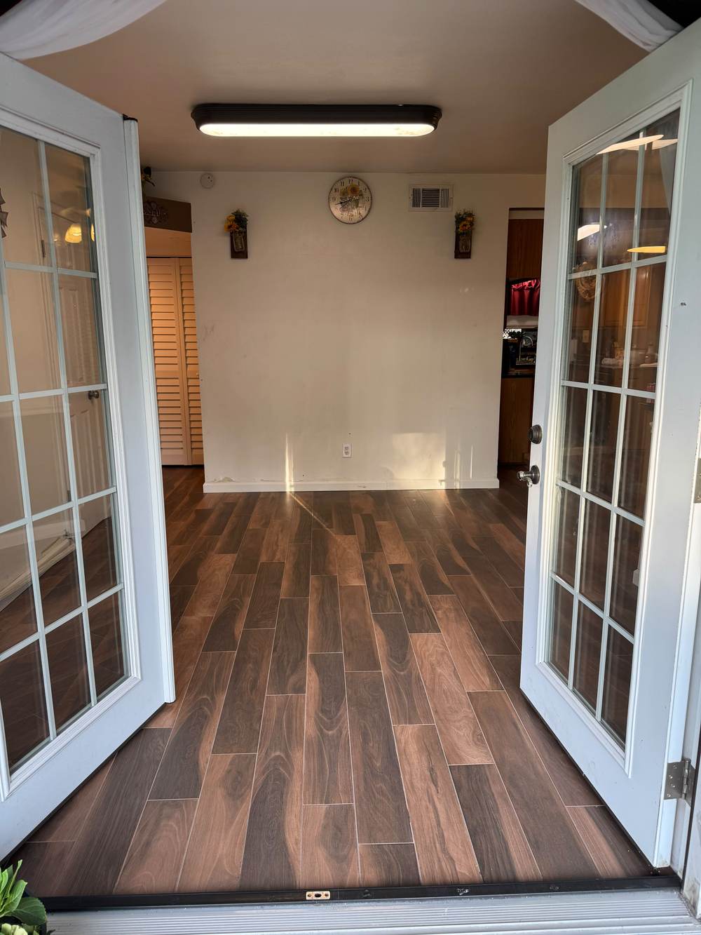 Wood-look tile flooring leading through French doors